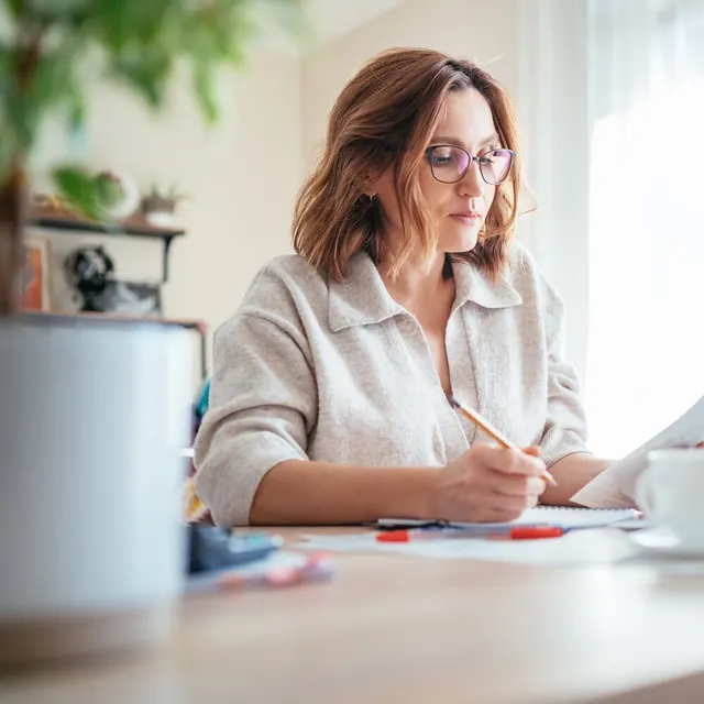 A woman working through paperwork at her desk