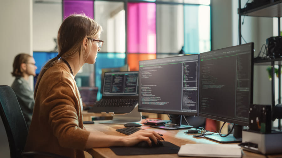 Developer working at multiple monitors in an office